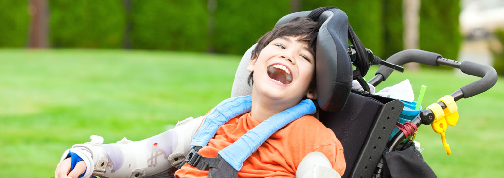 Image of a male primary school student smiling in a wheelchair, with an arm splint on both arms